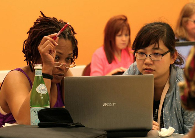 Two women discussing, looking at a laptop screen