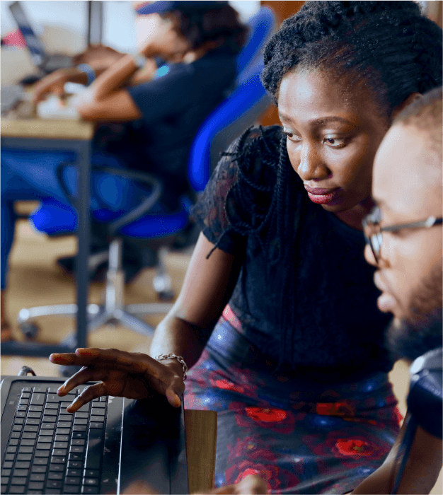 Two people discussing, facing a laptop